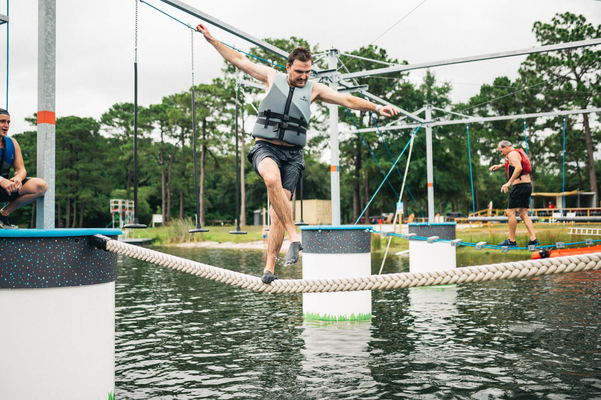 Adults having fun on the ropes course while balancing over the obstacles